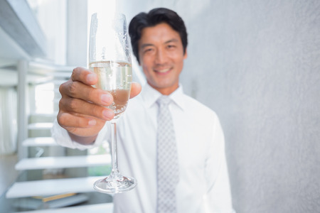 Happy man holding flute of champagne on the stairsの写真素材