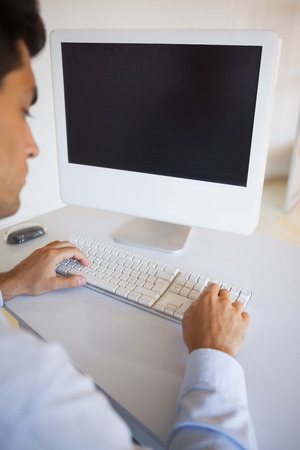 Businessman typing on keyboard at desk in his officeの写真素材