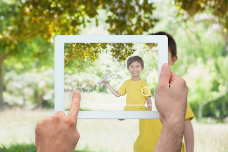 Hand holding tablet pc showing little boy holding paper airplaneの写真素材