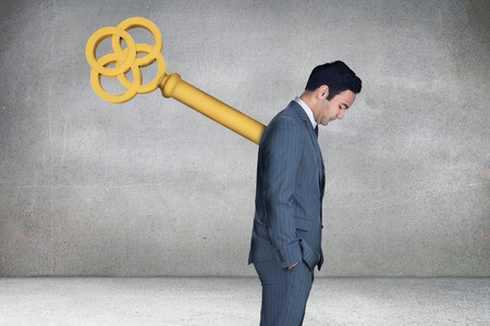 Composite image of wound up businessman with hands in pockets against grey roomの写真素材