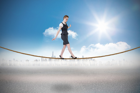 Businesswoman doing a balancing act against cityscape on the horizonの写真素材
