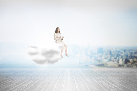 Businesswoman holding tablet and looking up against city scene in a roomの写真素材