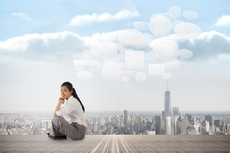 Businesswoman sitting cross legged with hands together against balcony overlooking cityの写真素材