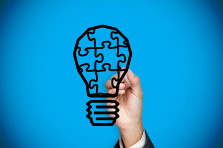 Composite image of businessman drawing light bulb against blue background with vignetteの写真素材