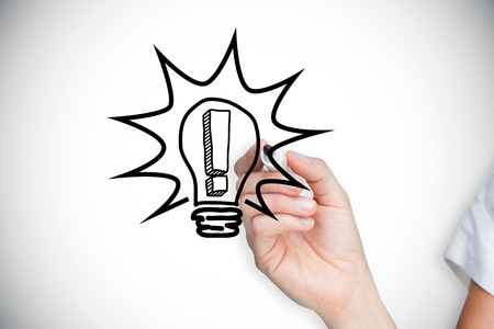 Composite image of businesswoman drawing light bulb against white background with vignetteの写真素材