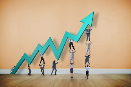 Business team holding up arrow against room with wooden floorの写真素材