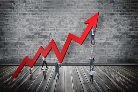 Business team holding up arrow against grey roomの写真素材