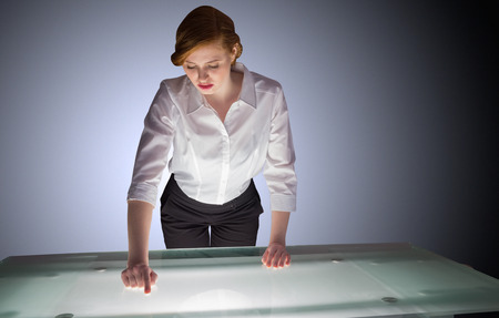 Redhead businesswoman standing and pointing on desk on shadow backgroundの写真素材