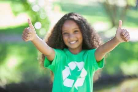 Young environmental activist smiling at the camera showing thumbs up on a sunny dayの写真素材