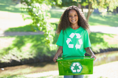 Young environmental activist smiling at the camera holding box on a sunny dayの写真素材