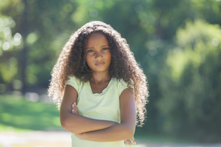 Young girl frowning at camera in the park on a sunny dayの写真素材