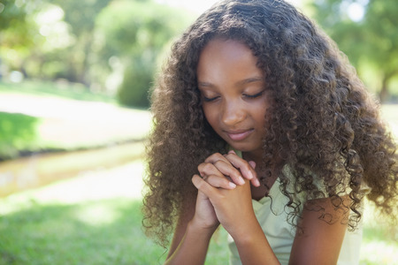 Young girl praying in the park on a sunny dayの写真素材