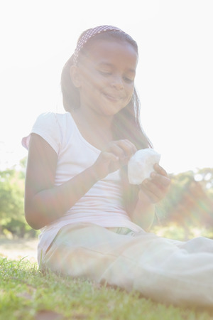 Little girl sitting on grass eating on a sunny dayの写真素材