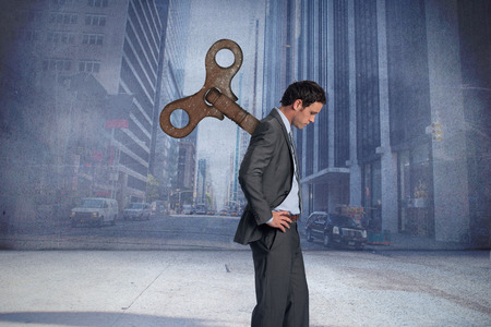 Wound up businessman with hands on hips against urban projection on wallの写真素材