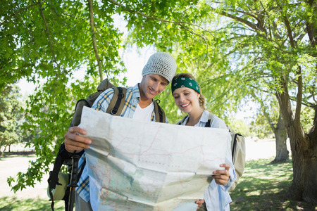 Active smiling couple on a hike consulting the map on a sunny day