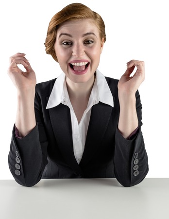 Excited redhead businesswoman sitting at desk on white backgroundの写真素材