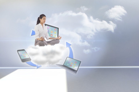 Businesswoman sitting in lotus pose against clouds in a roomの写真素材