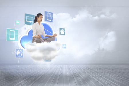 Businesswoman sitting in lotus pose against clouds in a roomの写真素材
