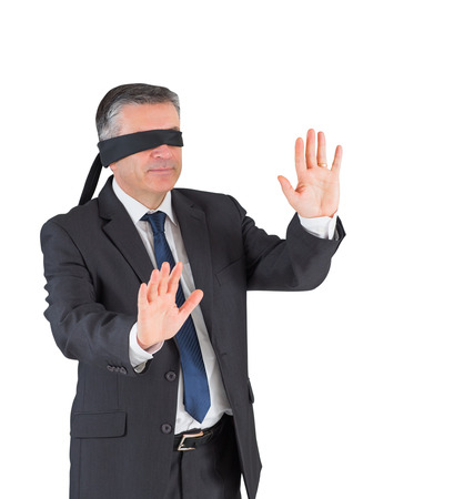 Mature businessman walking with blindfold on white backgroundの写真素材