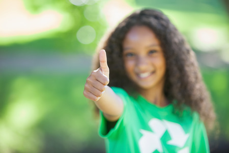 Young environmental activist smiling at the camera showing thumbs up on a sunny day