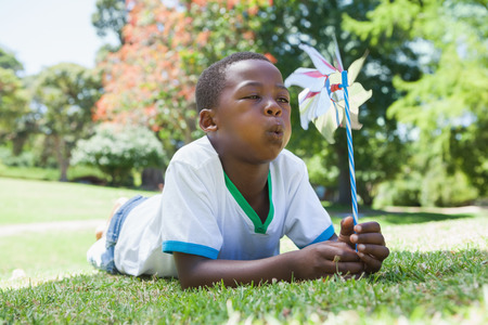 Little boy blowing pinwheel in the park on a sunny dayの写真素材