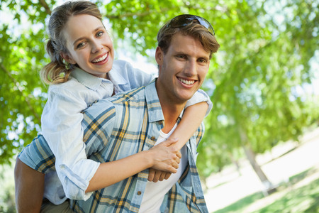 Happy couple smiling at camera in the park on a sunny dayの写真素材