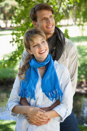 Cute couple standing and embracing in the park on a sunny dayの写真素材