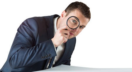 Businessman looking through magnifying glass on white backgroundの写真素材