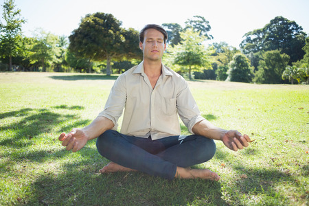 Stylish man meditating in the park on a sunny dayの写真素材