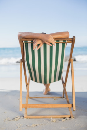 Woman relaxing in deck chair on the beach on a sunny dayの写真素材