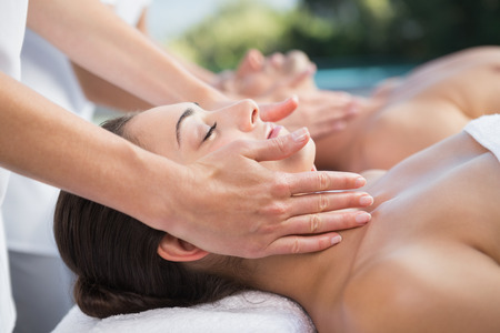 Peaceful couple enjoying couples massage poolside outside at the spa