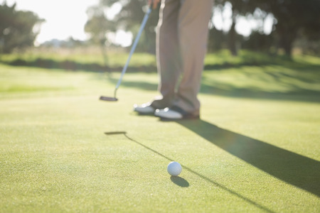 Golfer putting ball on the green on a sunny day at the golf courseの写真素材