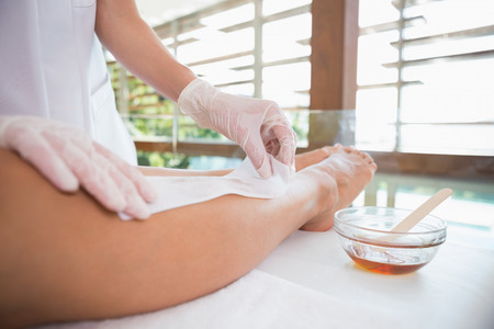 Woman getting her legs waxed by beauty therapist in the health spaの写真素材