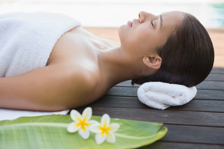 Peaceful brunette lying with eyes closed on a towel outside at the spaの写真素材