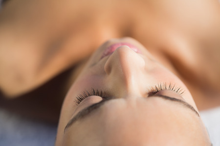 Smiling brunette lying on a towel outside at the spaの写真素材