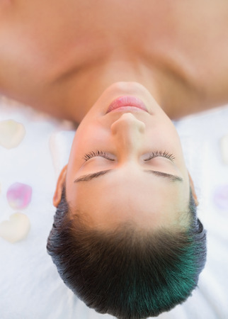 Calm brunette lying on towel with rose petals outside at the spaの写真素材