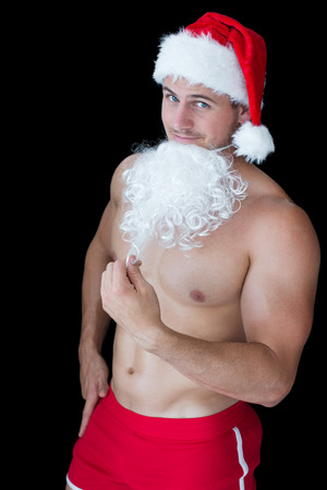 Smiling muscular man posing in sexy santa outfit with fake beard on black backgroundの写真素材
