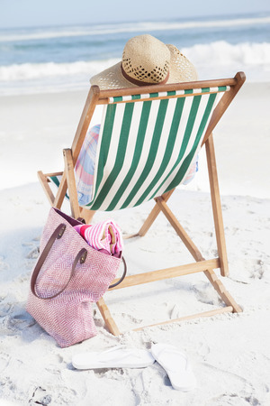 Woman in sunhat sitting on beach in deck chair on a sunny dayの写真素材