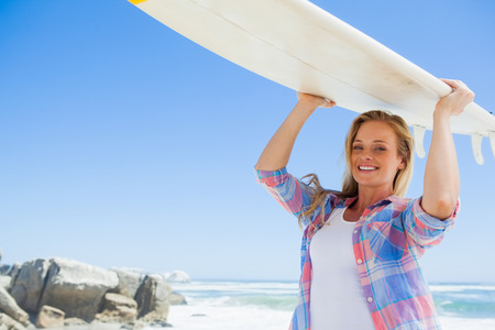 Blonde surfer holding her board smiling at camera on a sunny dayの写真素材