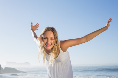 Pretty blonde smiling at the beach in white sundress on a sunny dayの写真素材
