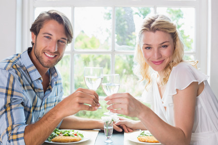 Cute smiling couple having a meal together at home in the dining roomの写真素材