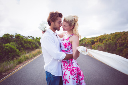 Cute couple standing on the road hugging on a sunny dayの写真素材