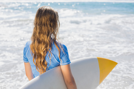 Fit surfer girl on the beach with her surfboard on a sunny day