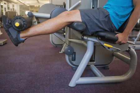 Focused man using weights machine for legs at the gym