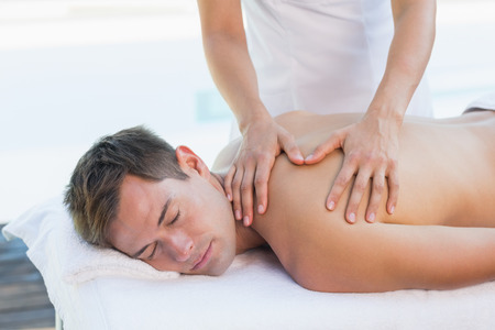 Handsome man getting a massage poolside outside at the spaの写真素材