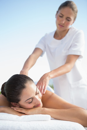 Calm brunette enjoying a massage poolside outside at the spaの写真素材