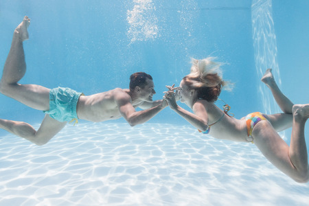 Cute couple kissing underwater in the swimming pool on their holidaysの写真素材