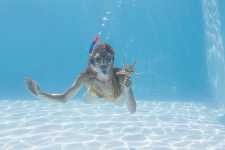 Cute blonde underwater in the swimming pool with snorkel and starfish on their holidaysの写真素材
