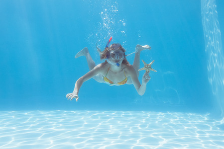 Cute blonde underwater in the swimming pool with snorkel and starfish on their holidaysの写真素材