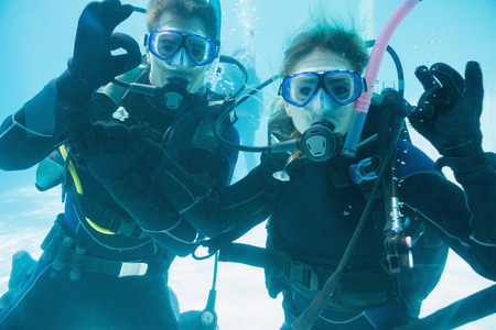  Friends on scuba training submerged in swimming pool looking to camera on their holidaysの写真素材
